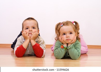 Two Kids Bored, Looking At Something - Laying On The Floor