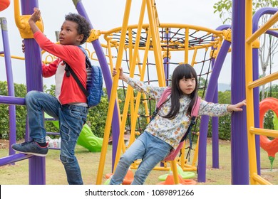 Two kids boy and girl having fun to play on children's climbing toy at school playground,back to school activity.kindergarten preschool
