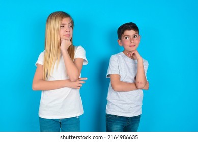 two kids boy and girl standing over blue background with hand under chin and looking sideways with doubtful and skeptical expression, suspect and doubt. - Powered by Shutterstock