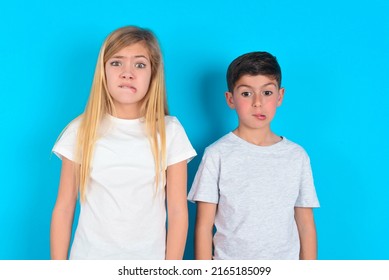 Two Kids Boy And Girl Standing Over Blue Background Being Nervous And Scared Biting Lips Looking Camera With Impatient Expression, Pensive.