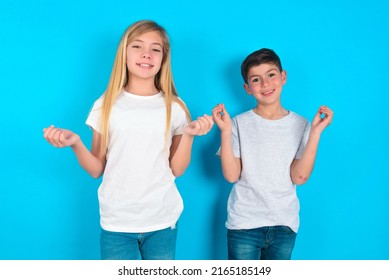 Two Kids Boy And Girl Standing Over Blue Background, Making Money Gesture.