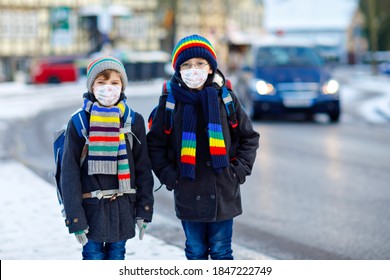 Two kids boys wearing medical mask on the way to school. Children with backpack satchel. Schoolkids on cold winter day with warm clothes. Lockdown and quarantine time during corona pandemic disease