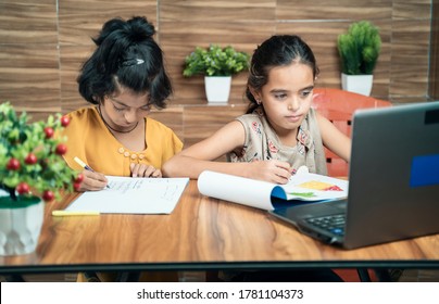 Two Kids Busy In Writing By Looking Into The Laptop During Online Or Virtual Class At Home - Concept Of E-learning Or Distance Learning Or Children Lifestyle During Coronavirus Or Covid-19 Pandemic.