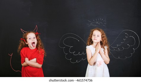 Two kids characters. Angry girl with imp horns and tail and a angel girl wings drawn on a blackboard. - Shutterstock ID 461574736