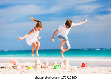 Two Kids Crushing Sandcastle On Summer Vacation