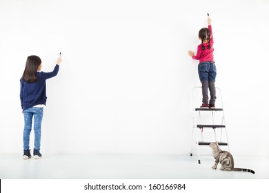 two kids drawing on the blank white wall 