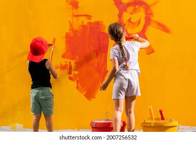 Two Kids  Holding Paintbrushes In Their Hands And Painting  Wall In Room