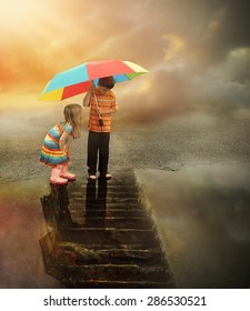 Two Kids Are Looking Down At A Rain Puddle Of Water With Stairs In The Reflection. The Boy Is Holding A Rainbow Umbrella For A Weather Or Imagination Concept.