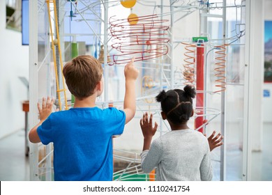 Two kids looking at a science exhibit,  back view
