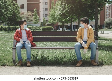 Two Kids With Medical Mask Maintain Social Distancing To Prevent From Virus Spreading  
Sitting On A Bench