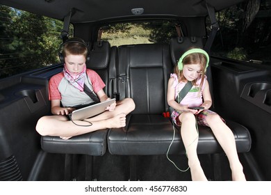 Two Kids On Technology In The Back Of A Car