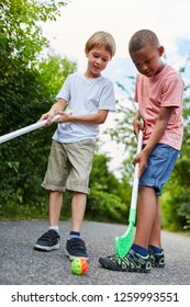 Two kids play together street hockey as friends