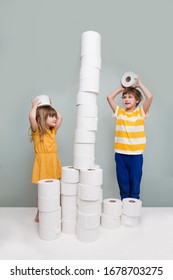 Two Kids Play Toilet Paper, Stand Tower In Home. Quarantine. Corona Virus. Stay Home Concept
