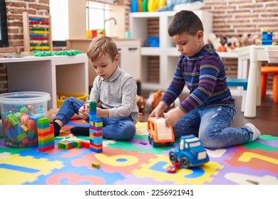 Two kids playing with construction blocks and truck toy sitting on floor at kindergarten - Shutterstock ID 2256921941