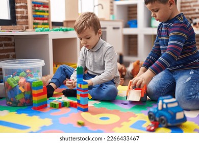 Two kids playing with construction blocks and truck toy sitting on floor at kindergarten - Shutterstock ID 2266433467
