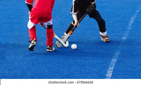 Two Kids Playing Field Hockey In Cold Weather On Wet Turf