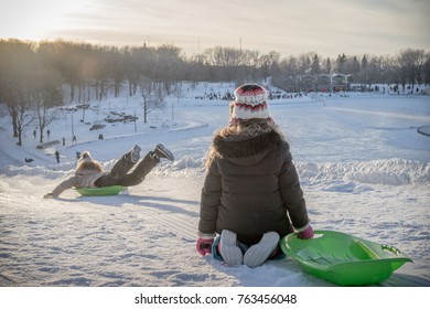 Two Kids Playing Outside In The Snow During A Sunny Winter Afthernoon With Their Sled