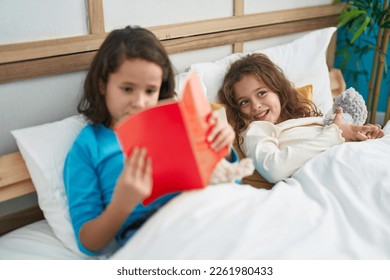Two kids reading story book sitting on bed at bedroom - Shutterstock ID 2261980433