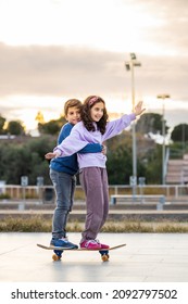 Two Kids Riding Together Wtih A Skate Board