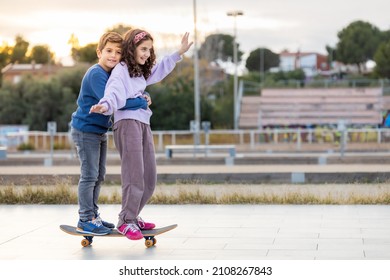 Two Kids Riding Together Wtih A Skate Board