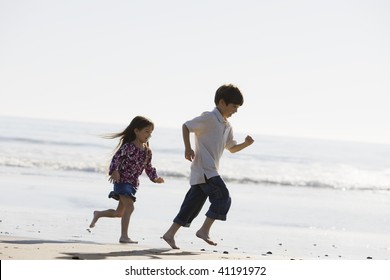 Two Kids Running Barefoot On The Sand At The Beach