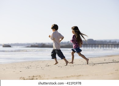 Two Kids Running Barefoot On The Sand At The Beach