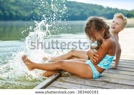 Two kids splashing water with their feet in summer