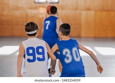 Two kids in sports attire watching a basketball game intensely, showcasing the back view of their jerseys and the sport ambiance - Powered by Shutterstock