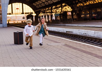 
two kids at the station with a big suitcase - Shutterstock ID 1551635561