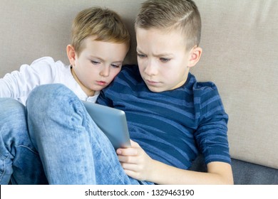 Two Kids Using Tablet Pc At Home, Modern Education Technology. Brothers With Tablet Computer In Light Room. Boys Playing Games On Tablet Computer, Emotions. Children's Internet Safety Concept