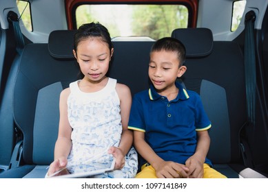 Two Kids Watching  Tablet In The Back Of A Car