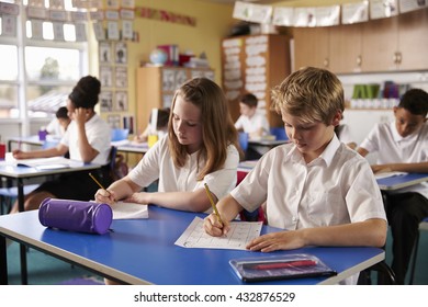 Two Kids Working At Desks In A Primary School Classroom