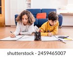 Two kids writing in notebooks, surrounded by pencils and a calculator, focused on their homework.