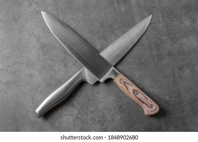 two knives on a gray table, top view, crossed like pirates