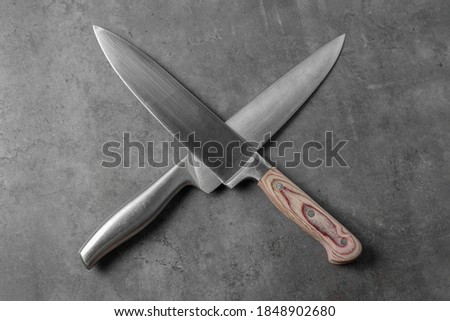two knives on a gray table, top view, crossed like pirates