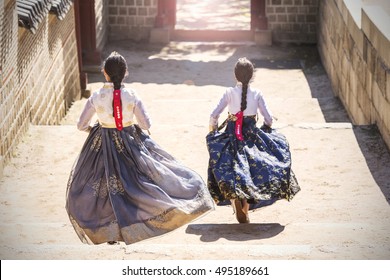 Two Korean Girls dressed in traditional dress running down stairs in Seoul street - Shutterstock ID 495189661