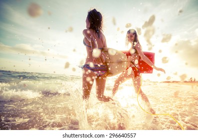 Two Ladies Running Into The Sea With Surf Boards