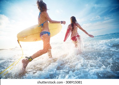 Two Ladies Running Into The Sea With Surf Boards