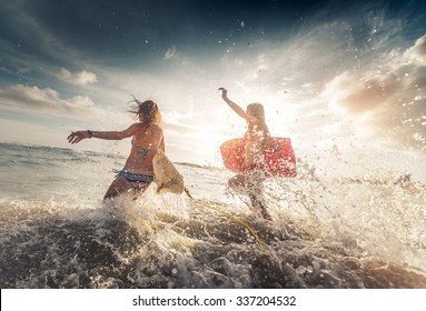 Two Ladies Running Into The Sea With Surf Boards