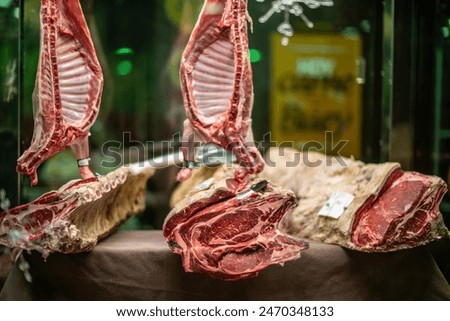 Two lamb carcasses and a beef rib hang in a Seville butcher shop, showcasing the premium quality of the meat.