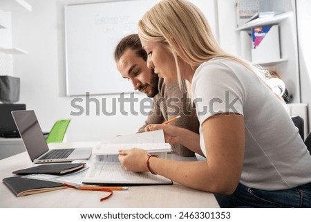 Two language learning students are focused on taking a test in their language class, showcasing their dedication to mastering a foreign tongue.	