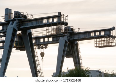 Two Large Bridge Cranes On The Background Of The Sky At Sunset. Outline Of A Girder Crane On A Cloud Background. Overhead Cranes