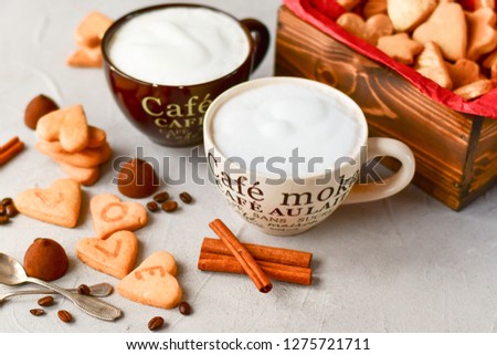 two large cups of coffee  and cookies in the form of hearts . romantic breakfast, romantic Valentine day. selective focus. on the сup description in French(mocha coffee, coffee with milk)