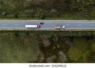 Two Large Freight Transporter Semi-trucks And A Car On The Road, Aerial View Top Down From Drone Pov