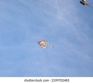 Two Large Kites Fly In The Blue Sky Tied With A String