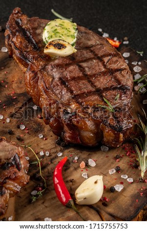 two large pieces of bone steak on wooden board next to sauce waiting for served ready.