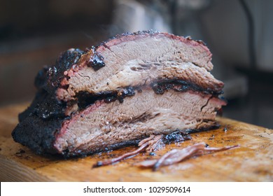 Two large pieces of smoked brisket meat on a wooden board