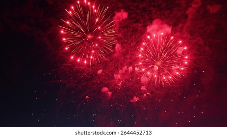 Two large red fireworks exploding in the night sky during a celebration, creating a festive atmosphere
