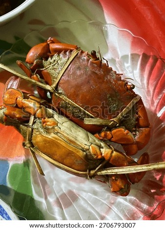 Two large, whole, cooked mud crabs (Scylla serrata) tied with bamboo string. One crab is bright orange-red, the other is lighter. Focus on fresh, delicious seafood.