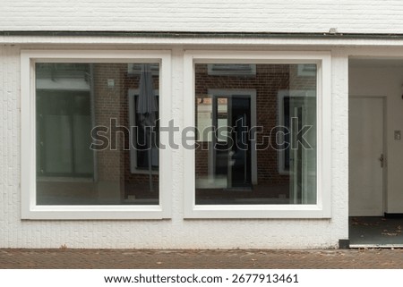 Two large windows reflecting a brick building in an empty commercial space, suggesting urban renewal or business opportunity